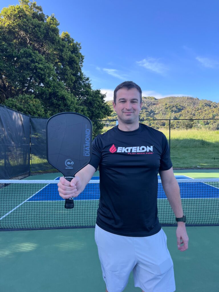 Man holding a sixzero double black diamond paddle.