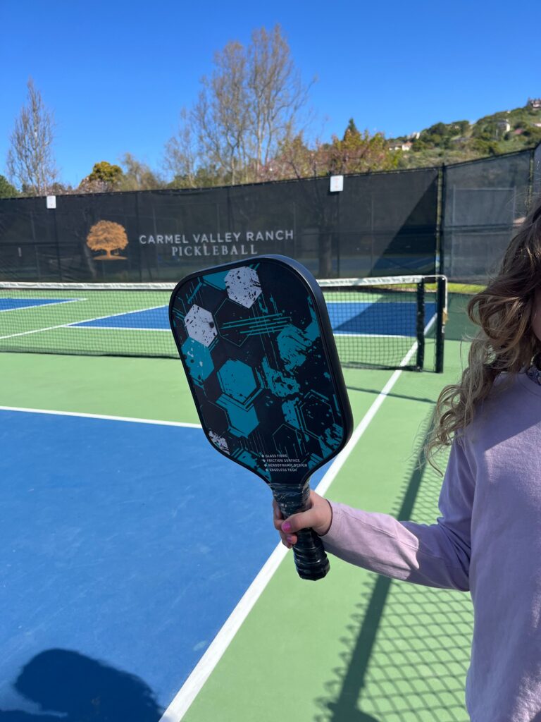 Picture of kid holding an adult pickleball paddle.