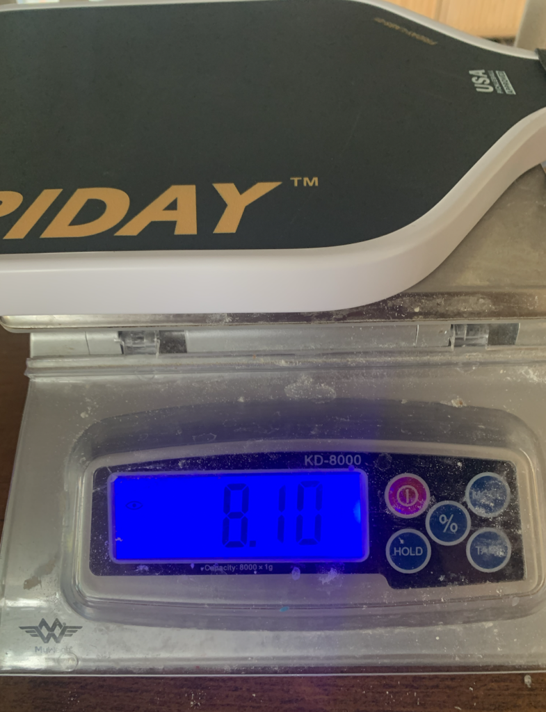 Picture of a scale showing the weight of the Friday pickleball paddle.