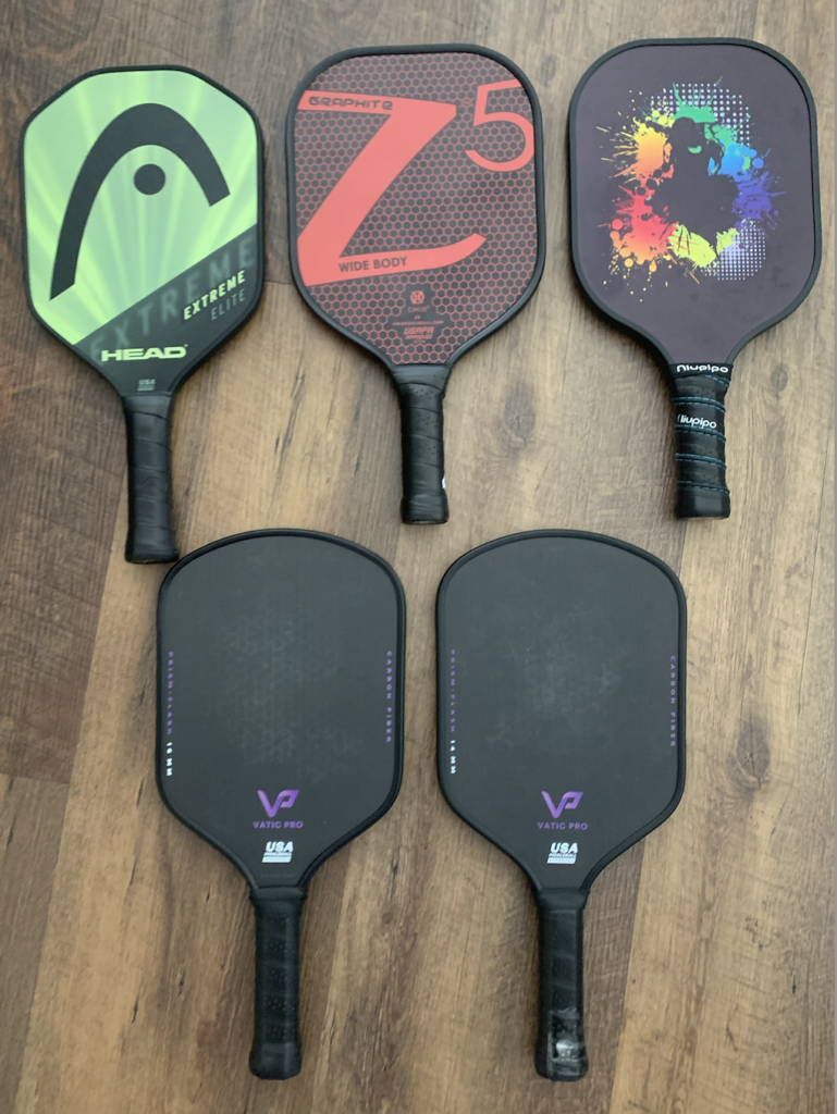 Picture of onix z5 graphite pickleball paddle next to 4 other paddles