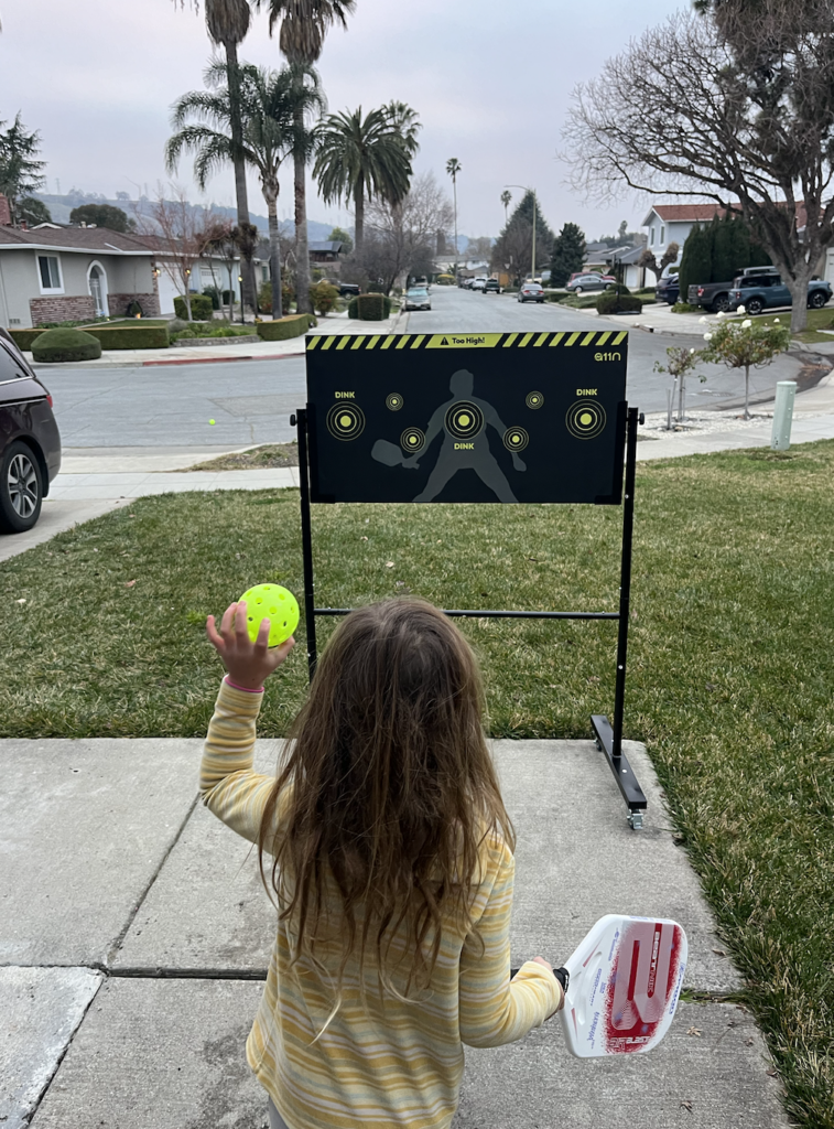 Picture of my kid playing practice drills with the pickleball practice board