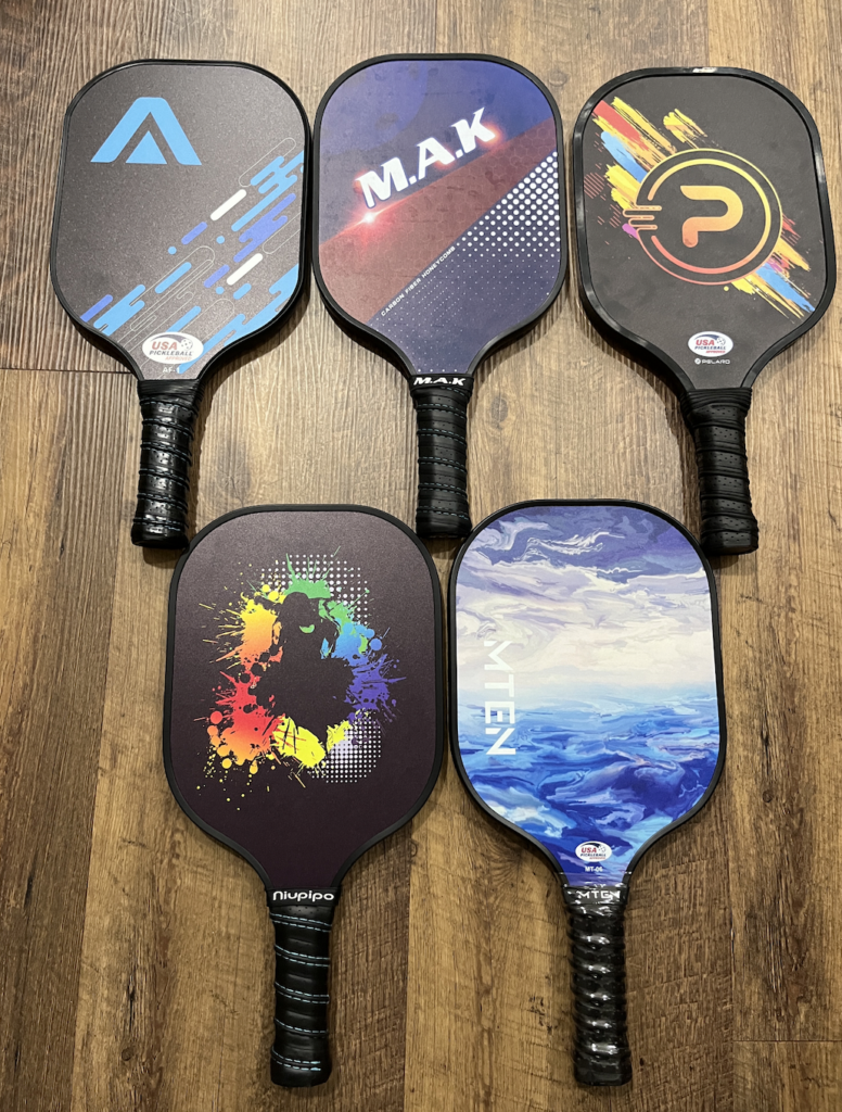 Picture of the MTEN pickleball paddle compared to 4 other fiberglass pickleball paddles.